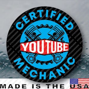 May include: A circular sticker with a black background featuring the text CERTIFIED YOUTUBE MECHANIC in blue. The center displays a blue gear icon with two crossed engine pistons and a red banner containing the white text YOUTUBE.