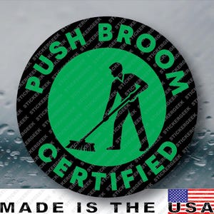 May include: A circular sticker with a black border and a green center. The text PUSH BROOM CERTIFIED is printed in green along the circular edge. In the center, a black silhouette of a person is shown using a push broom to sweep the floor.