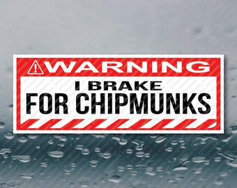 May include: A rectangular sticker with a red and white border. The top section reads "WARNING" in white letters on a red background. Below, the text "I BRAKE FOR CHIPMUNKS" is in bold black letters.