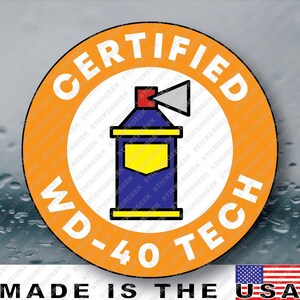 May include: A circular sticker featuring an orange border with the white text CERTIFIED and WD-40 TECH. In the center, a blue spray can icon with a yellow label and a red nozzle is depicted against a white background, with a gray spray cone.