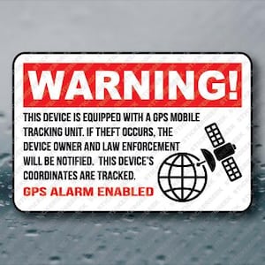 May include: A rectangular sticker with a white background and a red border. The word "WARNING!" is at the top in bold red letters. Below, the text reads: "THIS DEVICE IS EQUIPPED WITH A GPS MOBILE TRACKING UNIT...GPS ALARM ENABLED." A globe and satellite graphic are on the right.