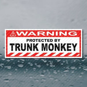 May include: Red and white warning sign with black text that reads "WARNING PROTECTED BY TRUNK MONKEY".