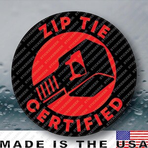 May include: A circular sticker with a black background and a red graphic of a zip tie. The text ZIP TIE CERTIFIED is printed in red capital letters around the perimeter of the circle. The sticker has a repeating watermark of the word STICKERGEEK.
