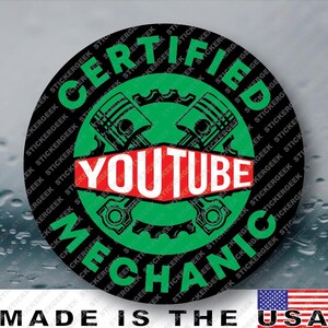 May include: A circular sticker with a black background featuring the green text CERTIFIED MECHANIC arranged in a circle. In the center, a green gear icon with two crossed engine pistons sits behind a red banner displaying the white text YOUTUBE.