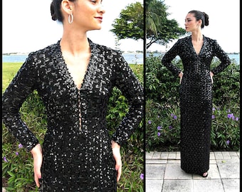 May include: A black sequined long-sleeved dress with a V-neckline. The dress is fitted and has a long skirt.