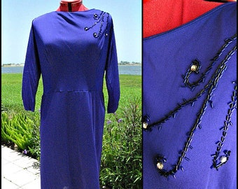 May include: A royal blue vintage dress with a boat neck and three-quarter sleeves. The dress features a beaded design on the shoulder and bodice.