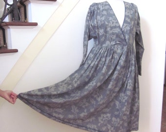 May include: A gray floral print dress with a V-neckline and long sleeves. The dress has a gathered skirt and a fitted bodice.