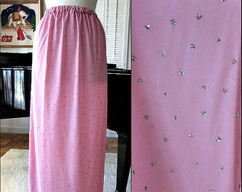May include: A long pink skirt with a subtle pattern of silver sequins. The skirt has a simple waistband and falls to the ankles.