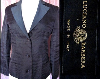 May include: A black blazer with a satin lapel and three buttons. The blazer has a textured fabric and a label that reads "Luciano Barbera Made in Italy".