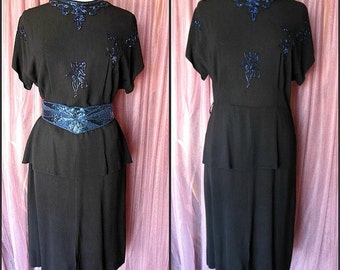 May include: A black dress with a blue sequined neckline and belt. The dress has a fitted bodice and a full skirt.