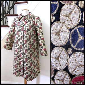 May include: A vintage coat with a geometric pattern in shades of gold, black, white, and red. The coat has a collar and a button closure.