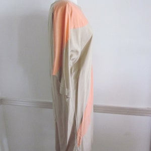 May include: A beige and peach colored dress with a geometric design. The dress is sleeveless and has a loose fit.