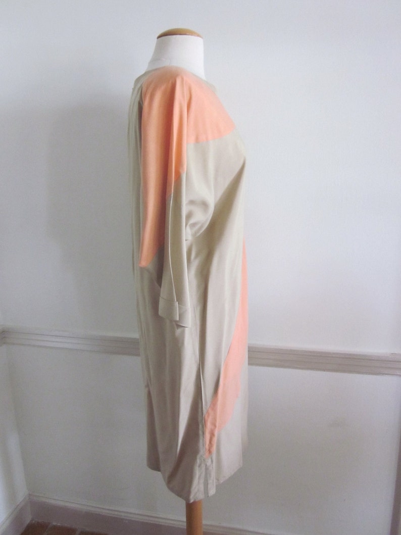 May include: A beige and peach colored dress with a geometric design. The dress is sleeveless and has a loose fit.