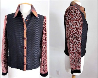 May include: A black and gray long-sleeved shirt with a leopard print on the sleeves and a wavy pattern on the front. The shirt has a button-up front and a collar.