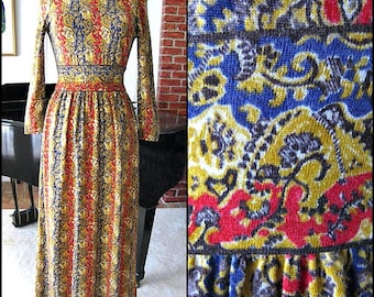 May include: A long-sleeved dress with a high neck and a paisley print in shades of blue, red, yellow, and brown. The dress has a fitted bodice and a flowing skirt.