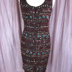 Puede incluir: Un vestido sin mangas de lentejuelas con un patr&oacute;n geom&eacute;trico en tonos negro, burdeos, dorado y turquesa. El vestido tiene una cremallera en la espalda y una abertura en la espalda.