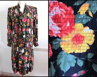 May include: A long-sleeved dress with a floral pattern in shades of red, yellow, and white on a dark green background. The dress has a V-neck and a pleated skirt. The fabric appears to be a lightweight material.