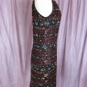 Puede incluir: Un vestido sin mangas de lentejuelas con un patr&oacute;n geom&eacute;trico en tonos burdeos, negro y turquesa.