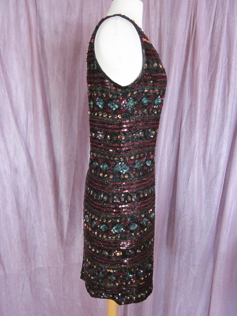 Puede incluir: Un vestido sin mangas de lentejuelas con un patr&oacute;n geom&eacute;trico en tonos burdeos, negro y turquesa.