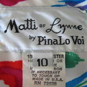 May include: White fabric with a colorful abstract print. A white label with black text reads "Matti of Lynne by PinaLo Voi". A smaller white label with black text reads "10", "Ester 1 or N", "Ron", "If necessary to touch up, made in U.S.A., RN 72508".