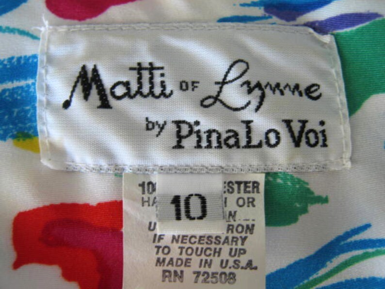 May include: White fabric with a colorful abstract print. A white label with black text reads "Matti of Lynne by PinaLo Voi". A smaller white label with black text reads "10", "Ester 1 or N", "Ron", "If necessary to touch up, made in U.S.A., RN 72508".