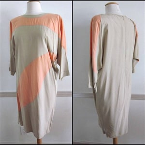 May include: A beige and peach colored dress with a geometric pattern. The dress has a loose fit and a round neckline.
