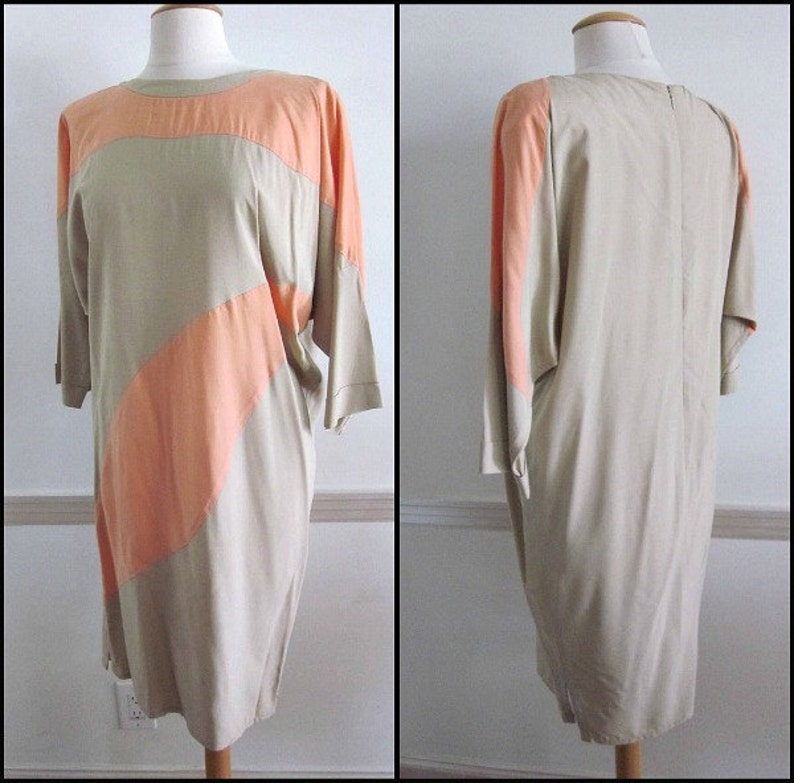 May include: A beige and peach colored dress with a geometric pattern. The dress has a loose fit and a round neckline.