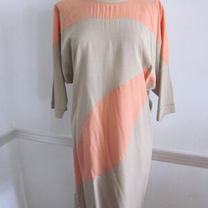 May include: A beige and peach color-blocked dress with a loose fit and three-quarter sleeves.