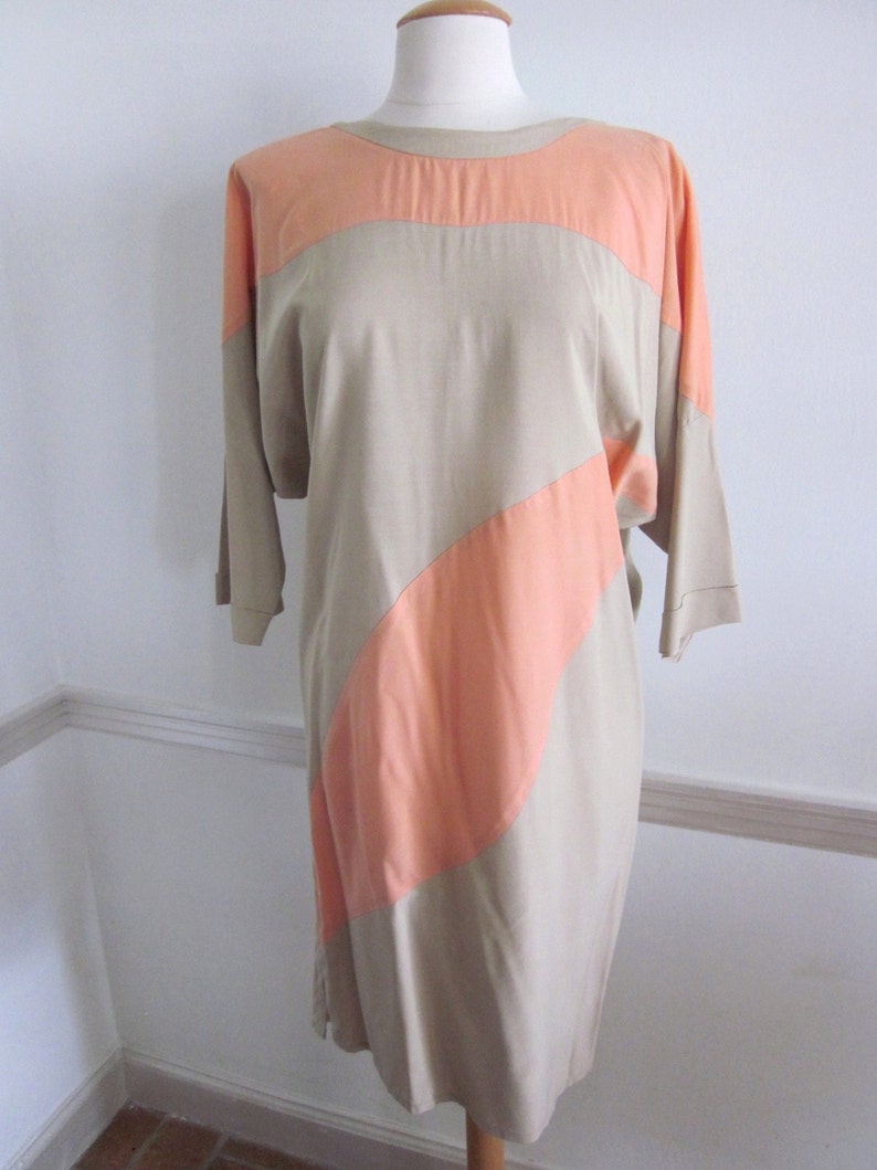 May include: A beige and peach color-blocked dress with a loose fit and three-quarter sleeves.