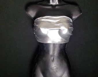May include: A black mannequin torso with a silver metallic bandeau top. The mannequin has a smooth, glossy finish and is posed against a dark background. The bandeau top is shiny and reflective.