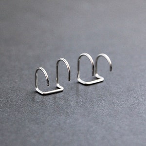 May include: Three silver metal nose rings, each with a different size and shape.