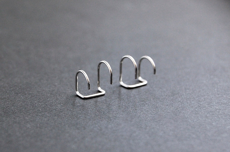 May include: Three silver metal nose rings, each with a different size and shape.
