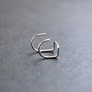 May include: Two silver hoop earrings, each with a simple, curved design.