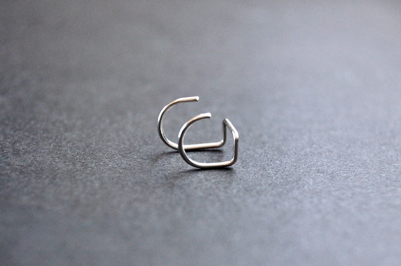 May include: Two silver hoop earrings, each with a simple, curved design.