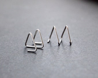 May include: Two pairs of silver triangle shaped earrings. One pair is a single triangle and the other pair is two triangles stacked on top of each other.