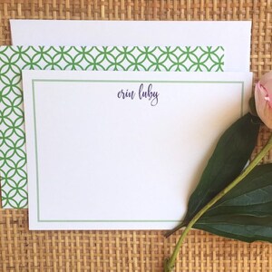 May include: A white card with a green border and a green patterned envelope. The card has the name "erin luby" written in purple ink.