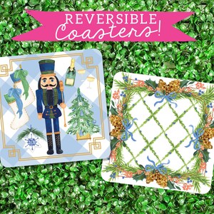 May include: Set of two reversible coasters featuring a blue and white checkered design with a nutcracker and a Christmas tree on one side and a wreath with blue ribbons on the other side.  REVERSIBLE COASTERS! text is displayed at the top of the image.