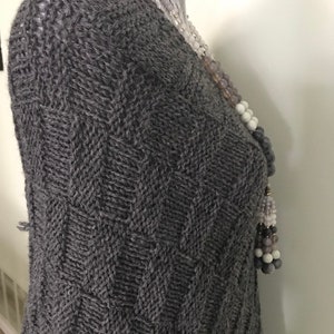 May include: A gray knitted sweater with a chevron pattern. The sweater is on a white mannequin.