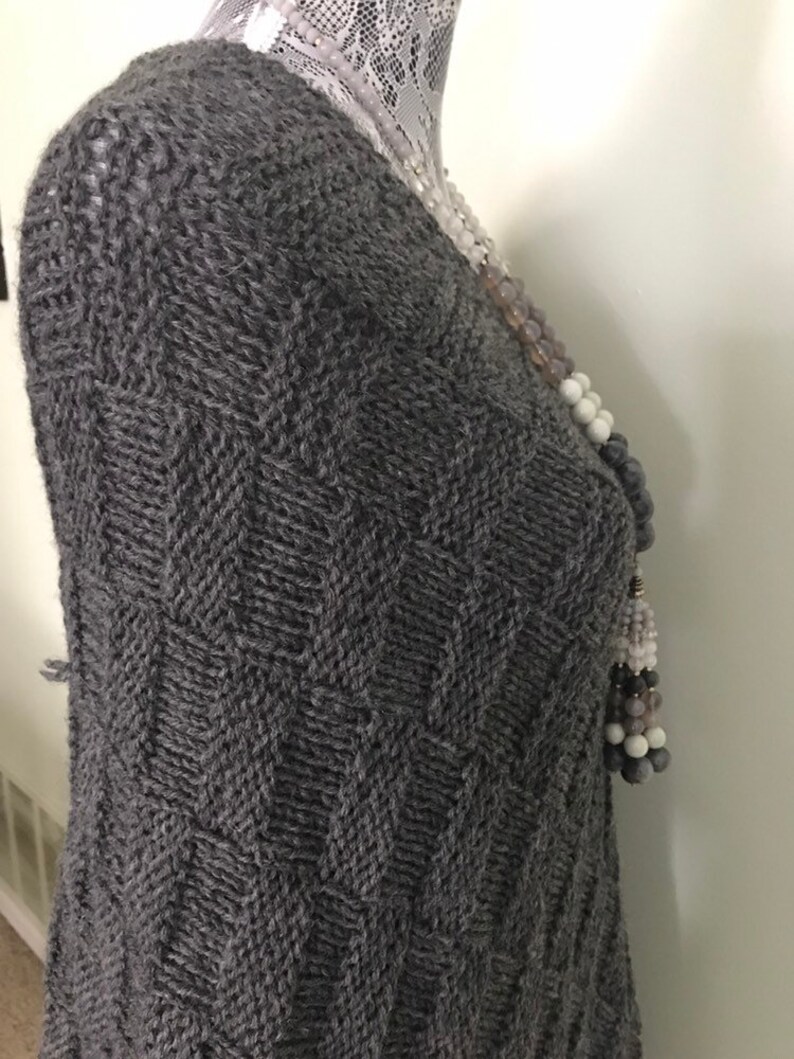 May include: A gray knitted sweater with a chevron pattern. The sweater is on a white mannequin.