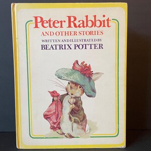 May include: A vintage hardcover book titled "Peter Rabbit and Other Stories" by Beatrix Potter. The cover features an illustration of Peter Rabbit wearing a hat and holding a flower. The book has a yellow border with green and red accents.
