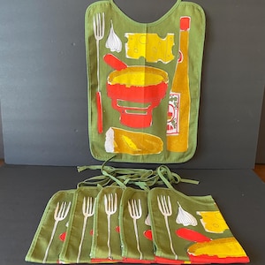 May include: A set of olive green bibs featuring a graphic print of a fondue pot, a piece of bread, a block of Swiss cheese, a garlic bulb, a fork, and a bottle of sauce. Each bib has fabric ties at the top for securing around the neck area.