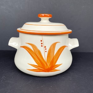 May include: A white ceramic soup tureen with a lid and two handles. The tureen has an orange floral design with brown dots.