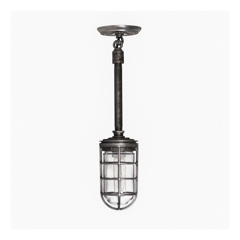 A rustic industrial pendant light with a metal cage and glowing bulb