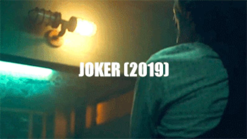 Film still screenshot from the 2019 movie Joker displaying Arthur Fleck in the gritty public bathroom scene, illuminated by a rustic double cage industrial wall sconce prop fixture handmade by MillerLights®.