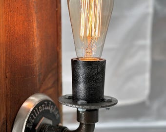 May include: A vintage-style wall sconce with a clear Edison bulb. The fixture is mounted on a stained wooden post. The metal components are black and silver, with the text "Miller Lights Est. 2012" on the base.