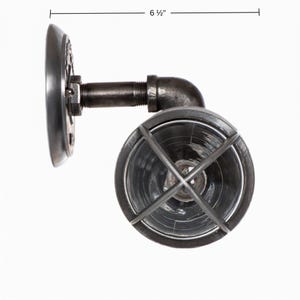 Side profile dimension diagram of 'The Joker' double cage vanity light fixture by MillerLights®, illustrating a total depth measurement of 6.5 inches from the wall bracket to the front of the metal protective wire cage guard.