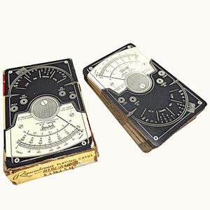 May include: A deck of playing cards featuring a black and white graphic design of a Triplett Model 310 multimeter on the back of each card. The cards are housed in a rectangular cardboard box labeled Remembrance Playing Cards with Redi-Slip Finish.