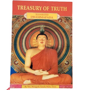 May include: A book titled Treasury of Truth Illustrated Dhammapada by Ven. Weragoda Sarada Maha Thero. The cover features a central image of a seated Buddha figure in orange robes against a circular, multi-colored, intricate mandala background.