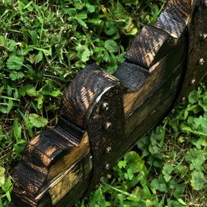 May include: A wooden wall decor piece with a black and brown finish. The piece is shaped like a series of overlapping arches and has metal accents.