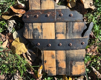 May include: A wooden cutout of the state of Wisconsin, made from reclaimed whiskey barrel staves. The state shape is outlined in black metal and secured with rivets. The wood has a natural brown color with black charring.